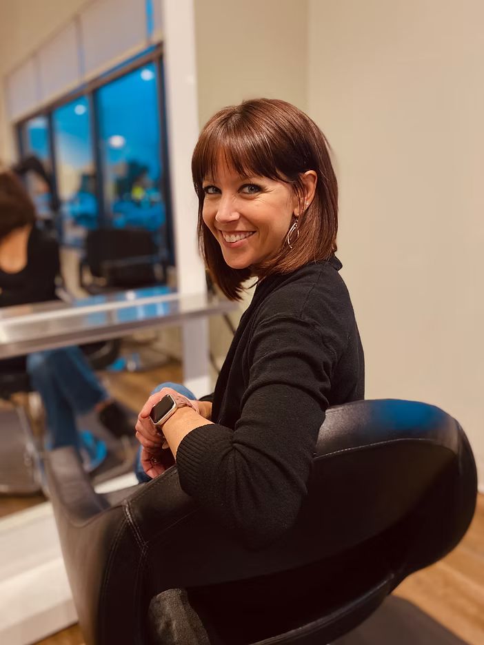 Colleen Collier smiling in a salon chair at her studio in Mendon, NY